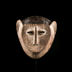 Front view of a Lega mask featuring large ears, narrow eyes and a light patina.