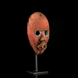 Vue trois quarts d’un masque de feu Dan Zakpei Ge en bois couvert de tissu rouge.