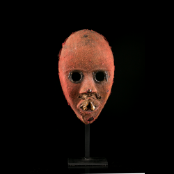 Front view of a Dan Zakpei Ge fire mask with circular eyes and deeply patinated red cloth.