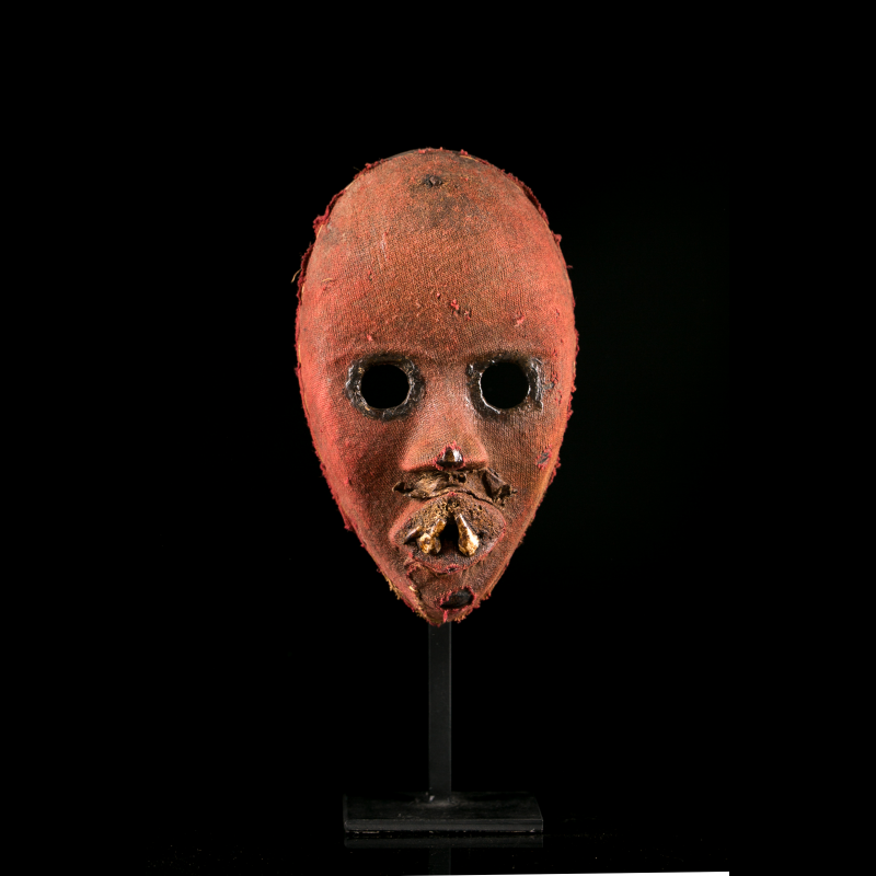 Front view of a Dan Zakpei Ge fire mask with circular eyes and deeply patinated red cloth.