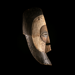 Side view of Songye Kifwebe mask showing tall crest and strongly projecting geometric facial features.
