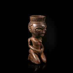 Three-quarter view of a traditional Pende carved wooden vessel.