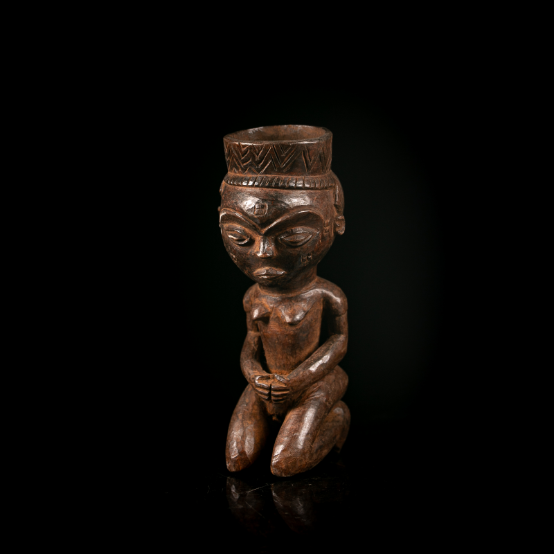 Vue de face d'une coupe anthropomorphe Pende en bois sculpté représentant une figure humaine agenouillée.