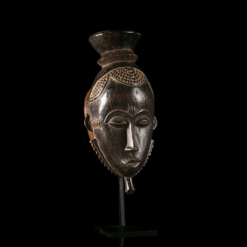 Baoulé Mblo wooden mask from Ivory Coast displayed on a custom metal stand.