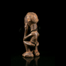 Rear view of a Chokwe wooden figure showing the crosshatched hairstyle and bead ornaments.