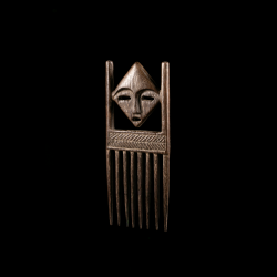 Vue de trois-quarts d'un peigne traditionnel Lega en bois présentant un visage janiforme.