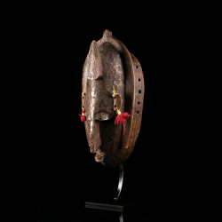 Profil d'un masque Marka traditionnel présentant son décor métallique gravé.