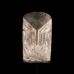 Mbole Yela flat wooden mask with white patina displayed on a custom metal stand.