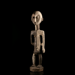 Vue trois-quarts d'une statue africaine Metoko Kakungu présentant une décoration blanche et noire gravée.