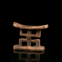 Vue opposée d’un appuie-nuque Mfinu du Congo avec assise incurvée et quatre ouvertures rectangulaires.