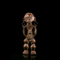 Vue de face d'une statuette Zande en bois sculpté avec anneaux métalliques aux oreilles.