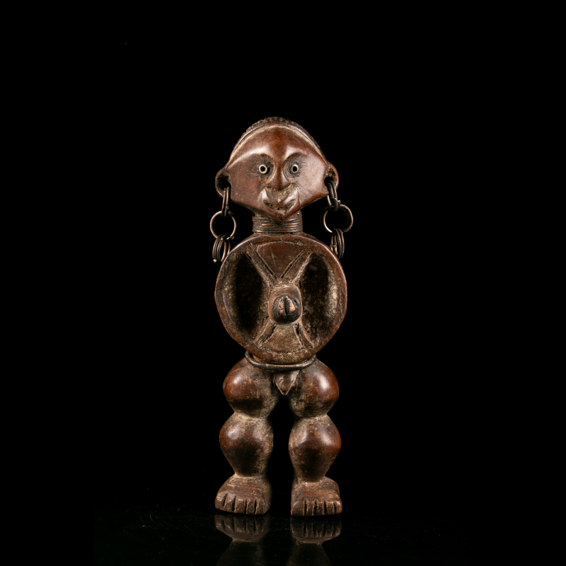 Vue de face d'une statuette Zande en bois sculpté avec anneaux métalliques aux oreilles.
