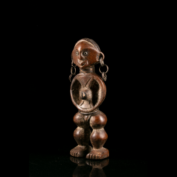 Side view of a Zande wooden sculpture with inset eyes and metal earrings.