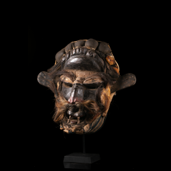 Powerful Wè Guéré mask in wood, fiber and hair displayed on its stand.