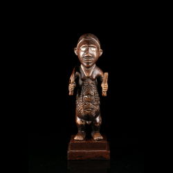 Vue de face d’une statuette d’ancêtre Bembe Biteki avec attributs tenus dans les mains et décor géométrique du torse.