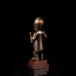 Rear view of a Bembe Beembe wooden ancestor figure from the Congo displayed on a wooden base.