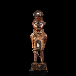Vue frontale de la statue de pouvoir Kongo avec yeux incrustés, bouche dentée et charges rituelles.