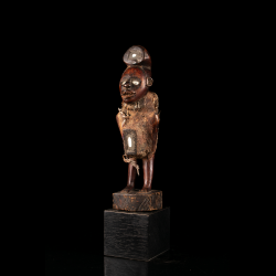 Figure de pouvoir Kongo nkisi de 23 cm avec coiffure recourbée, matières rituelles et socle noir.