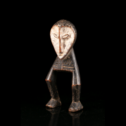 Vue de trois quarts d’une sculpture Lega Katanda en bois sculpté et pigment clair, associée au Bwami.
